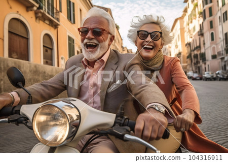 Happy mature couple riding a scooter in the city on a sunny day Happy mature couple riding a scooter in the city on a sunny day 104316911