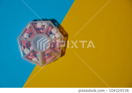 Organizer weekly shots medical pill box with doses of tablets for daily take medicine with white pink drugs and capsules. Copy space Daily vitamins at home. Health care and diseases cure Organizer weekly shots medical pill box with doses of tablets for daily take medicine with white pink drugs and capsules. Copy space Daily vitamins at home. Health care and diseases cure 104320536