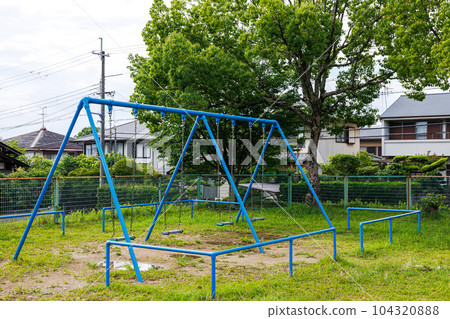 A stationary swing in a park in a residential area 104320888