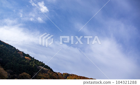 Blue sky and white clouds flowing over the mountaintop Blue sky and white clouds flowing over the mountaintop 104321288