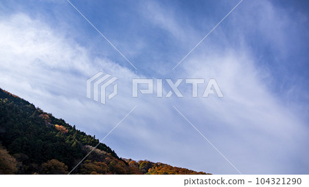 Blue sky and white clouds flowing over the mountaintop Blue sky and white clouds flowing over the mountaintop 104321290
