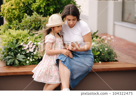 Mom and daughter looking pictures on phone. Beautiful girls using phone outdoor 104322475