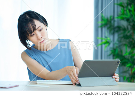 A woman touching a computer with an uneasy expression 104322584