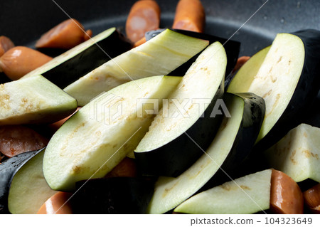 煎鍋裡煎茄子和維也納香腸的烹飪場景。 煎鍋裡煎茄子和維也納香腸的烹飪場景。 104323649