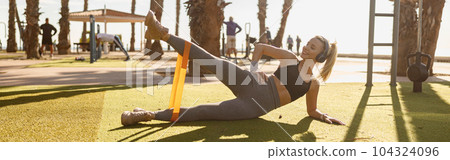 Caucasian woman exercising with resistance band outdoors 104324096