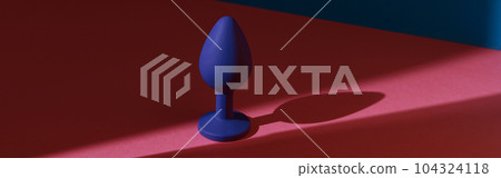 Blue buttplug sex toy on a colorful background. Photo of anal toy for adult with contrast shadows 104324118