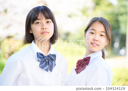 Two junior high school girls standing side by side outdoors 104324129