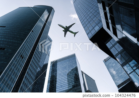 Airplane flying on business skyscrapers of financial center. Travel, economy, cargo, transportation concept Airplane flying on business skyscrapers of financial center. Travel, economy, cargo, transportation concept 104324476