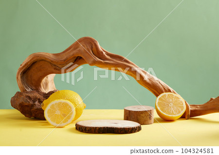 Minimalist creative background for cosmetic or product presentation with ingredient from lemon. On a green background, dry twigs decorated with fresh lemon and lemon slices. Front view Minimalist creative background for cosmetic or product presentation with ingredient from lemon. On a green background, dry twigs decorated with fresh lemon and lemon slices. Front view 104324581