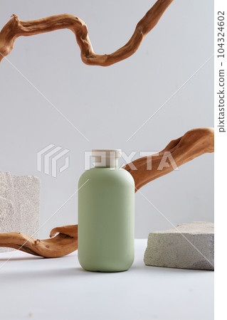 Abstract background for branding and minimal presentation with an empty green bottle unbranded on white background with dry twigs and gray stone. Space for design, front view Abstract background for branding and minimal presentation with an empty green bottle unbranded on white background with dry twigs and gray stone. Space for design, front view 104324602