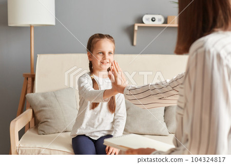 Warm conversation doctor psychologist with little schoolgirl with mental trauma, specialist and cute patient giving five after good psychological therapy session meeting. 104324817
