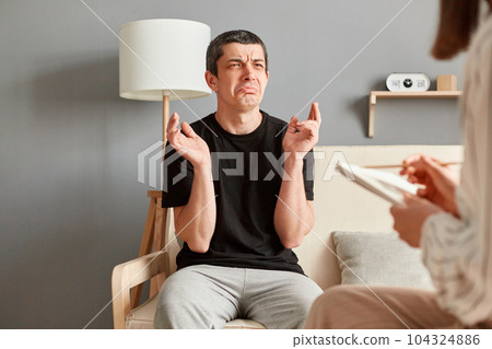 Man and woman having psychology session at psychology center, upset guy crying telling about his problems, specialist making notes about his condition. 104324886