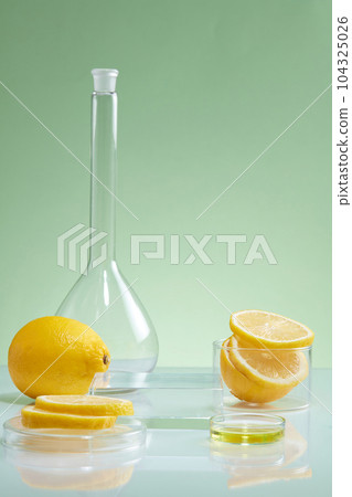 Laboratory concept with glassware containing lemon slices. Empty podium for cosmetic promotion. Lemon (Citrus limon) is very useful to enhance skin condition 104325026