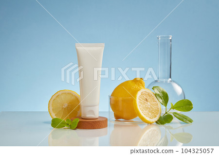 A wooden podium with a white tube placed on, decorated with some laboratory glassware. The benefits of Lemon (Citrus limon) for skin are numerous 104325057