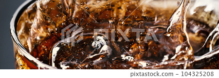 Splashing of Cola and Ice. Cola soda and ice splashing fizzing or floating up to top of surface. Close up of ice in cola water. Texture of carbonate drink with bubbles in glass. Cold drink background Splashing of Cola and Ice. Cola soda and ice splashing fizzing or floating up to top of surface. Close up of ice in cola water. Texture of carbonate drink with bubbles in glass. Cold drink background 104325208