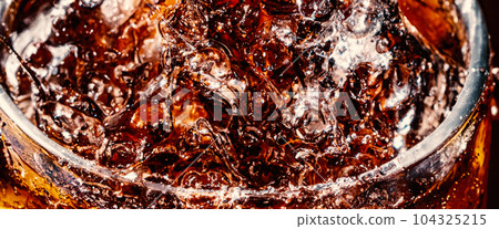 Splashing of Cola and Ice. Cola soda and ice splashing fizzing or floating up to top of surface. Close up of ice in cola water. Texture of carbonate drink with bubbles in glass. Cold drink background Splashing of Cola and Ice. Cola soda and ice splashing fizzing or floating up to top of surface. Close up of ice in cola water. Texture of carbonate drink with bubbles in glass. Cold drink background 104325215