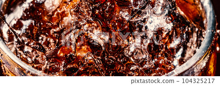 Splashing of Cola and Ice. Cola soda and ice splashing fizzing or floating up to top of surface. Close up of ice in cola water. Texture of carbonate drink with bubbles in glass. Cold drink background Splashing of Cola and Ice. Cola soda and ice splashing fizzing or floating up to top of surface. Close up of ice in cola water. Texture of carbonate drink with bubbles in glass. Cold drink background 104325217
