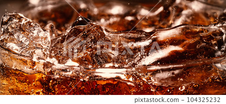 Splashing of Cola and Ice. Cola soda and ice splashing fizzing or floating up to top of surface. Close up of ice in cola water. Texture of carbonate drink with bubbles in glass. Cold drink background Splashing of Cola and Ice. Cola soda and ice splashing fizzing or floating up to top of surface. Close up of ice in cola water. Texture of carbonate drink with bubbles in glass. Cold drink background 104325232