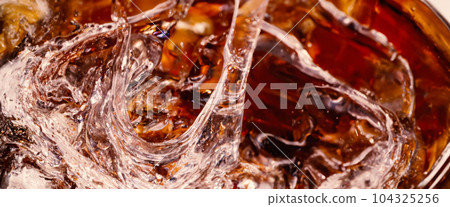 Splashing of Cola and Ice. Cola soda and ice splashing fizzing or floating up to top of surface. Close up of ice in cola water. Texture of carbonate drink with bubbles in glass. Cold drink background 104325256