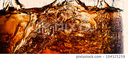 Splashing of Cola and Ice. Cola soda and ice splashing fizzing or floating up to top of surface. Close up of ice in cola water. Texture of carbonate drink with bubbles in glass. Cold drink background 104325259