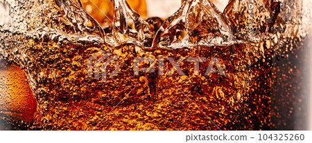 Splashing of Cola and Ice. Cola soda and ice splashing fizzing or floating up to top of surface. Close up of ice in cola water. Texture of carbonate drink with bubbles in glass. Cold drink background 104325260