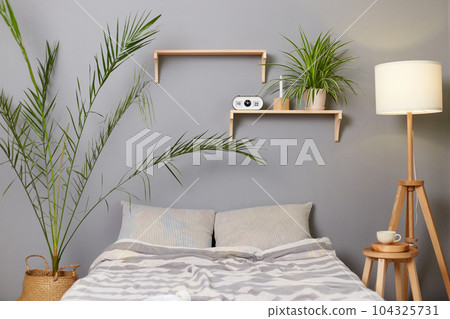 Modern stylish bedroom with gray walls decor on shelves flowers and lamp. Modern stylish bedroom with gray walls decor on shelves flowers and lamp. 104325731