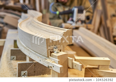 Bending wooden staircase handrail made of oak planks and plywood on table closeup. Detail of stairs fence in carpentry workshop Bending wooden staircase handrail made of oak planks and plywood on table closeup. Detail of stairs fence in carpentry workshop 104326392