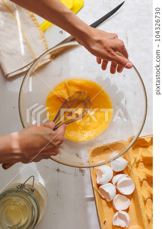 top view of woman beating eggs for an omelette or pie. Cook delicious and healthy food  104326730