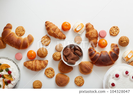 Baking background. Flat lay of different sugary desserts cakes, cookies, croissant, bagel on table. Text space, top view. Baking background. Flat lay of different sugary desserts cakes, cookies, croissant, bagel on table. Text space, top view. 104328047