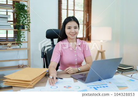 Portrait of a woman business owner showing a happy smiling face as he has successfully invested her business using computers and financial budget documents at work. Portrait of a woman business owner showing a happy smiling face as he has successfully invested her business using computers and financial budget documents at work. 104328853