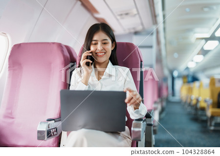 Asian business woman passenger sitting on business class luxury plane while working using smart phone mobile talking or video conference and travel concept. Asian business woman passenger sitting on business class luxury plane while working using smart phone mobile talking or video conference and travel concept. 104328864