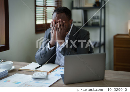 Burnout American African business man in stress works with many paperwork document, migraine attack, Freelance, work from home. 104329040
