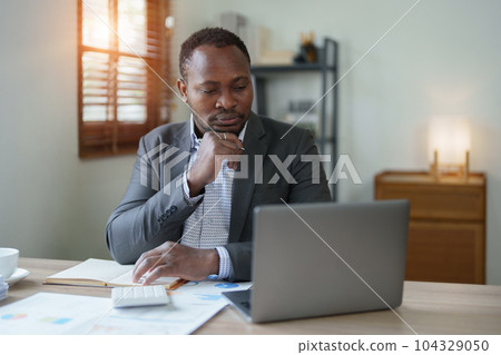 middle aged man American African using computer laptop with planning working on financial document, tax, exchange, accounting and Financial advisor. auditor or audit concepts. 104329050