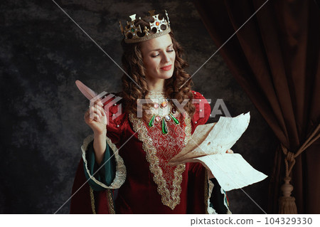 happy medieval queen in red dress with parchment and crown happy medieval queen in red dress with parchment and crown 104329330