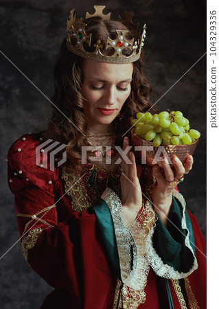 medieval queen in red dress with plate of grapes and crown medieval queen in red dress with plate of grapes and crown 104329336