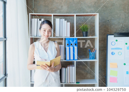 Portrait of a woman business owner showing a happy smiling face as he has successfully invested her business using computers and financial budget documents at work. Portrait of a woman business owner showing a happy smiling face as he has successfully invested her business using computers and financial budget documents at work. 104329750