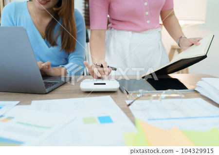 Financial analysts analyzing business reports on planned investment projects during corporate meeting discussions showcase successful teamwork with marketing plan, computers and calculators to work. 104329915
