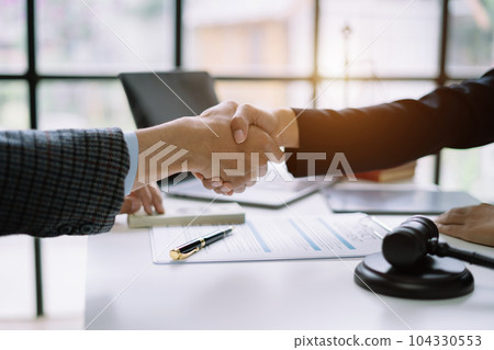 Lawyer shaking hands with client after discussing final contract agreement. 104330553