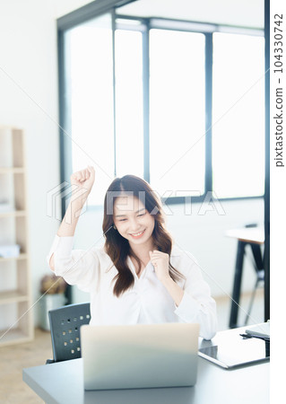 Portrait of a woman business owner showing a happy smiling face as he has successfully invested her business using computers and financial budget documents at work. 104330742