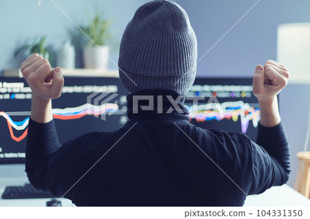 Back view portrait of hipster man broker looking at computer monitors and do winner gesture, clenched fists, celebrating successful trade on stock market, wearing gray cap. 104331350
