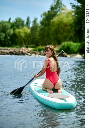 Woman relaxing on sup surfboard, floating on water, recreational sports, paddle boarding. Woman relaxing on sup surfboard, floating on water, recreational sports, paddle boarding. 104332144