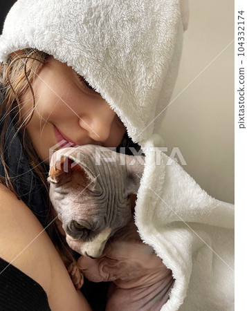 Lovely little child girl after bath embracing cat and smiling at home 104332174