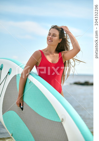 Surfer female at beach, girl in red swimwear enjoying surfing, summer vacation and extreme sport. 104332206