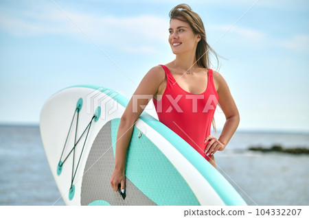 Surfer girl with board on sandy beach, beautiful young woman at beach enjoying water sports. Surfer girl with board on sandy beach, beautiful young woman at beach enjoying water sports. 104332207