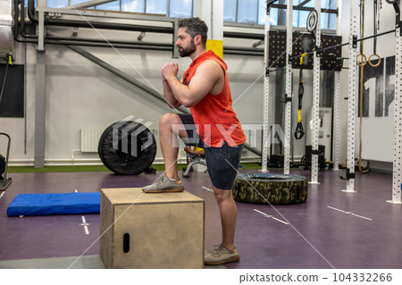 Young strong man doing workout with wooden box step up in crossfit gym. Young strong man doing workout with wooden box step up in crossfit gym. 104332266