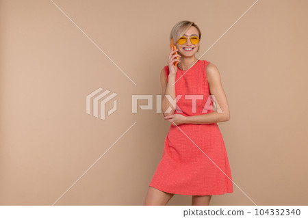 Pleased smiling woman in dress and sunglasses talking cell phone Pleased smiling woman in dress and sunglasses talking cell phone 104332340