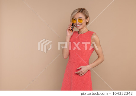 Pleased smiling woman in dress and sunglasses talking cell phone Pleased smiling woman in dress and sunglasses talking cell phone 104332342