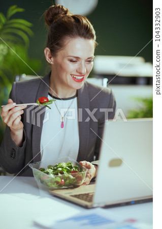 happy accountant woman in green office eating salad 104332903