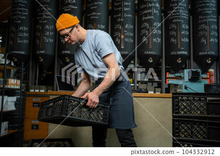 Bartender barista uploads paper coffee packages in boxes on roasting factory or coffee shop. Bartender barista uploads paper coffee packages in boxes on roasting factory or coffee shop. 104332912