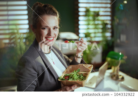 happy bookkeeper woman in green office eating salad 104332922